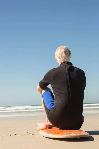 Idoso sentado na prancha de surf — Fotografia de Stock