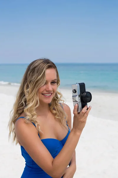 Mulher sorridente fotografando na praia — Fotografia de Stock