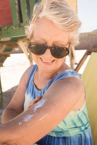 Femme âgée appliquant une lotion solaire — Photo