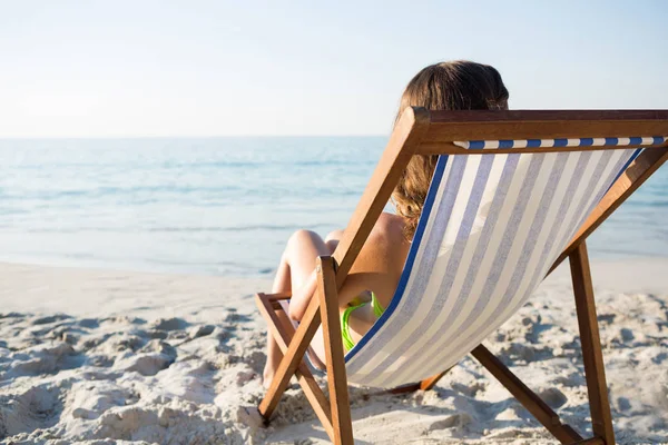 Vrouw ontspannen op lounge stoel op strand — Stockfoto