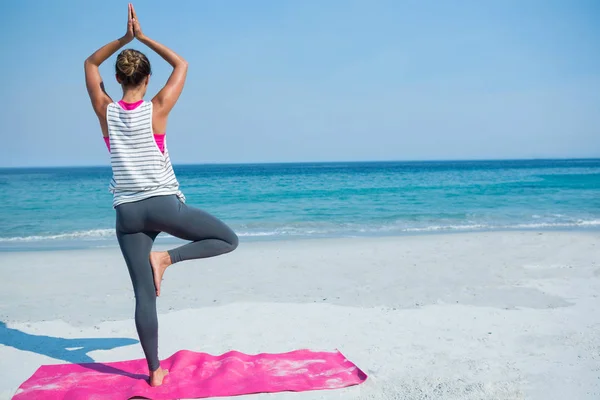 Donna che pratica yoga in posa albero in spiaggia — Foto Stock