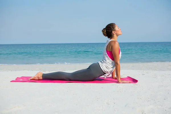 Woman practicing cobra pose at beach — Stock Photo, Image