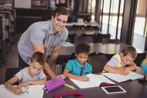 Profesor ayudando a los escolares con la tarea — Foto de Stock