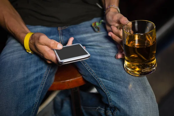 Homem usando telefone celular enquanto bebe cerveja — Fotografia de Stock