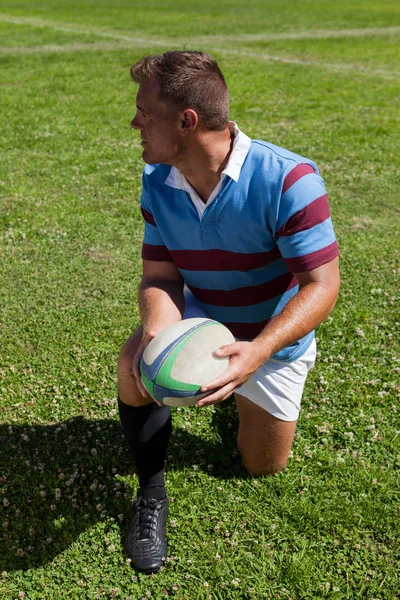 Jugador arrodillado y sosteniendo la pelota — Foto de Stock