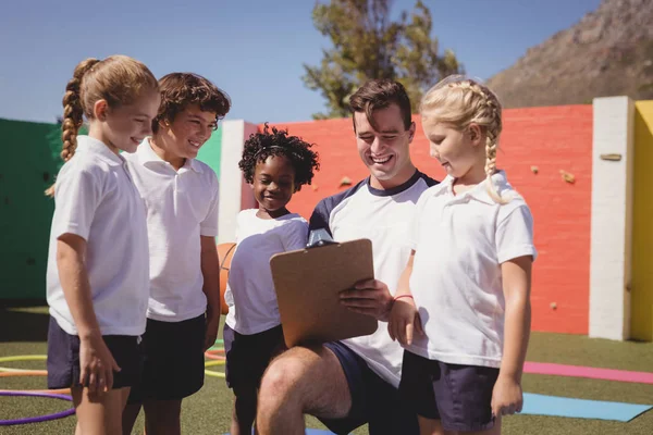 Coach en schoolkinderen bespreken op Klembord — Stockfoto