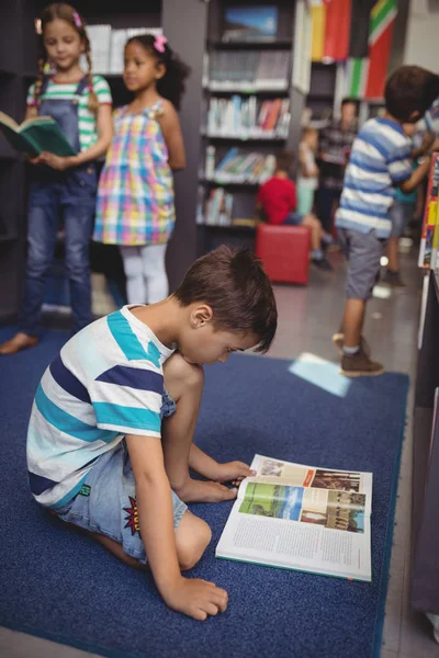 Attente schooljongen leesboek in bibliotheek — Stockfoto