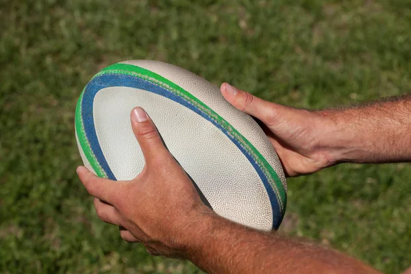 Manos sosteniendo pelota de rugby —  Fotos de Stock