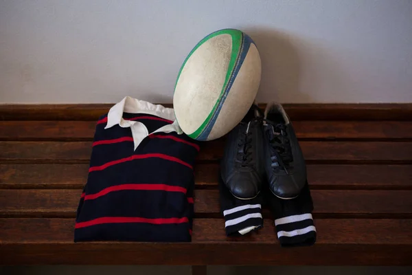 Rugby boll och kläder på bänk — Stockfoto