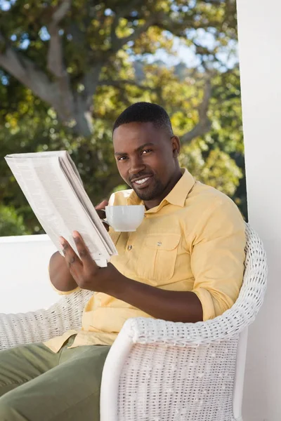Άνθρωπος που κρατά φλιτζάνι καφέ, διαβάζοντας εφημερίδα — Φωτογραφία Αρχείου