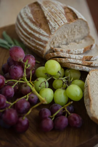 Panes y uvas marrones en tabla de cortar —  Fotos de Stock
