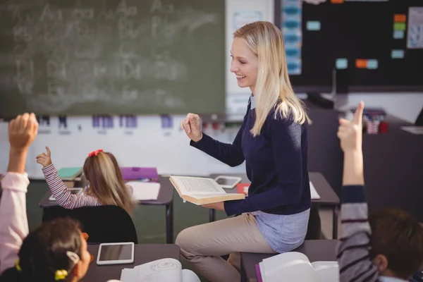 Schoolkinderen verhogen handen terwijl leraar lesgeven — Stockfoto