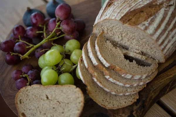 Pane e uva marroni sul tagliere — Foto Stock