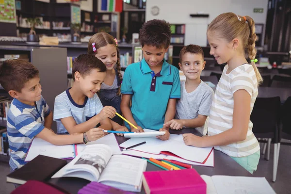 Figyelmes schoolkid tabletta használata a könyvtárban — Stock Fotó