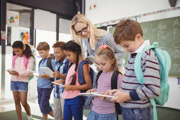 Professor assistindo crianças em idade escolar em tablet — Fotografia de Stock