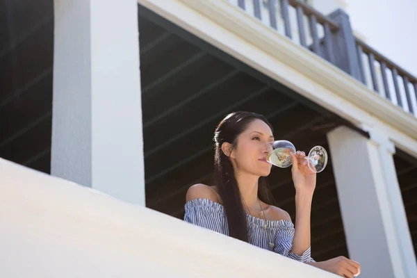 Mulher bebendo vinho branco na varanda — Fotografia de Stock