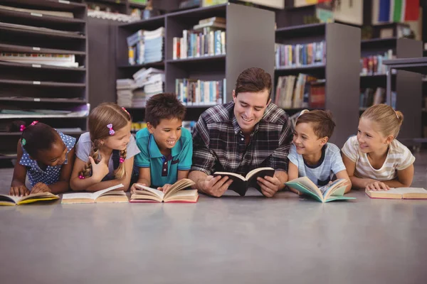 Leraar en schoolkinderen liggend op de vloer — Stockfoto