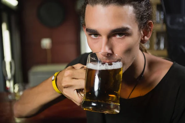 Мужчина выпивает кружку пива за стойкой — стоковое фото