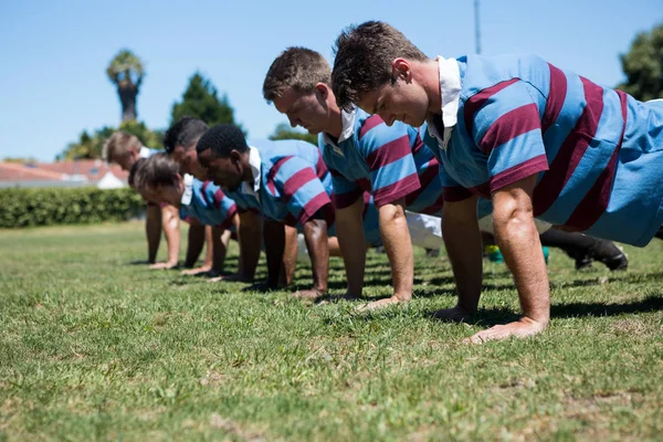 Players doing push up at grassy field — Stock Photo, Image