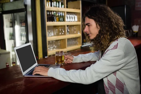 Hombre tomando cerveza mientras usa el portátil — Foto de Stock