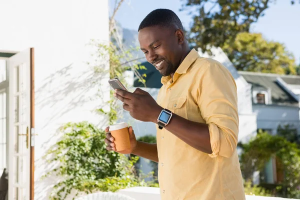 Uomo utilizzando smartphone mentre tiene il caffè — Foto Stock