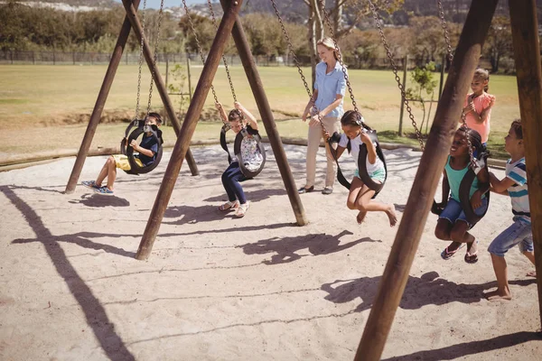 Trainer guiding schoolkids on swing — Stock Photo, Image