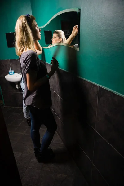 Mujer aplicando delineador de ojos mientras mira el espejo — Foto de Stock