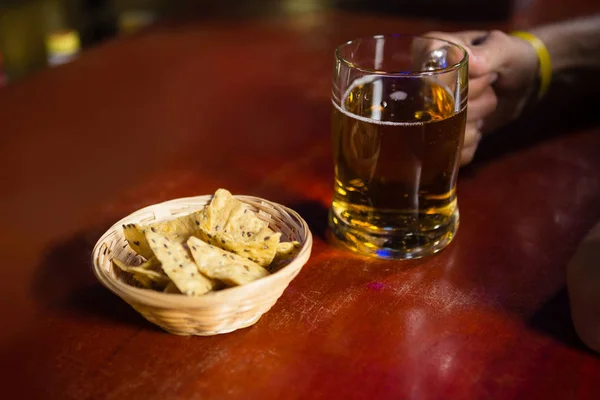 Mano de hombre sosteniendo una taza de cerveza con merienda — Foto de Stock