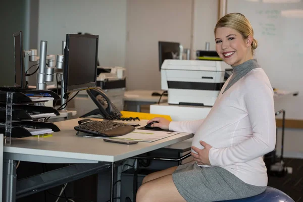 Femme enceinte assise au bureau — Photo