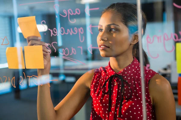 Female executive looking at sticky notes — Stock Photo, Image