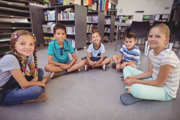 Gelukkig schoolkinderen zitten in bibliotheek — Stockfoto