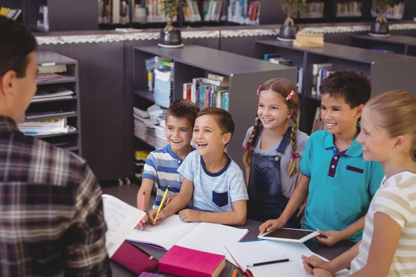 Écoliers interagissant avec le professeur à la bibliothèque — Photo