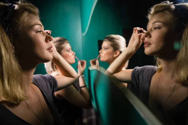 Mujer aplicando delineador de ojos mientras mira el espejo — Foto de Stock