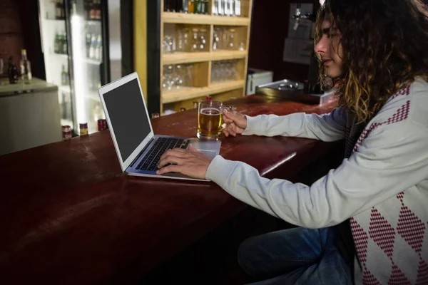 Hombre tomando cerveza mientras usa el portátil — Foto de Stock