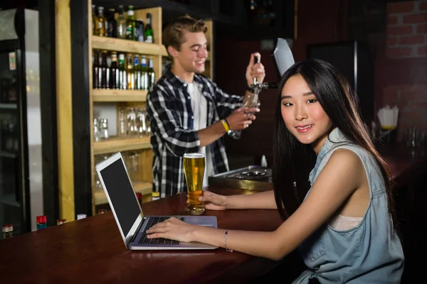 同时使用笔记本电脑在喝啤酒的女人吧 — 图库照片