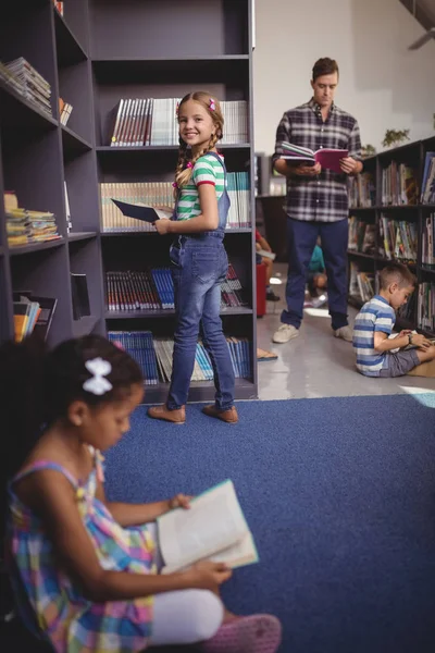 Školačka výběr knih z police v knihovně — Stock fotografie