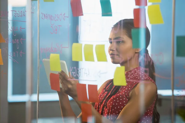 Executive using digital tablet near glass board — Stock Photo, Image