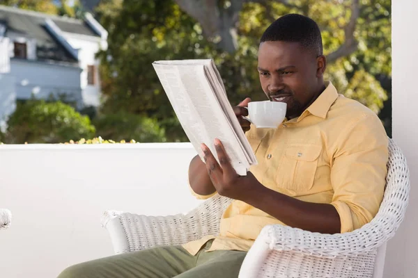 Uomo che tiene il caffè durante la lettura del giornale — Foto Stock