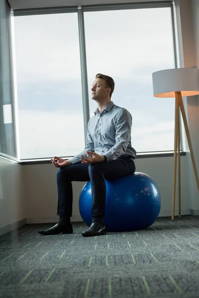 Executivo meditando sobre bola de fitness — Fotografia de Stock