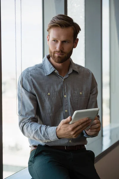 Male executive using tablet near window — Stock Photo, Image