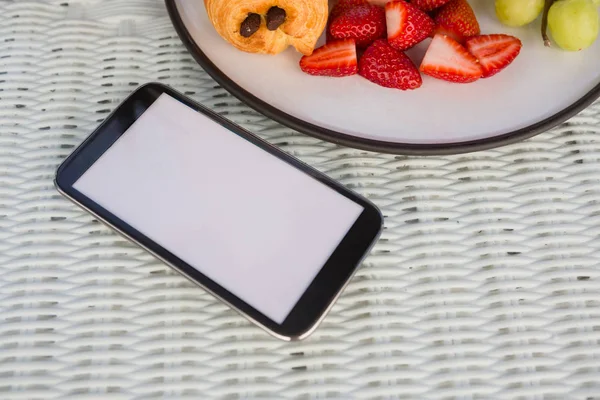 Teléfono móvil por frutas en la mesa en la cafetería — Foto de Stock