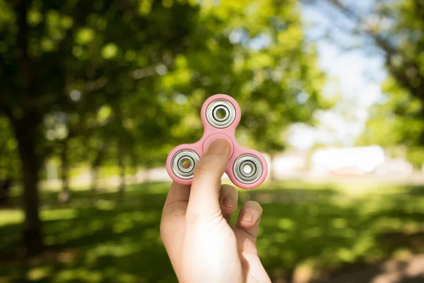 Menina segurando um fidget spinner em um parque — Fotografia de Stock
