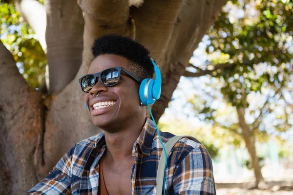 Uomo con occhiali da sole e cuffie che ascolta musica — Foto Stock