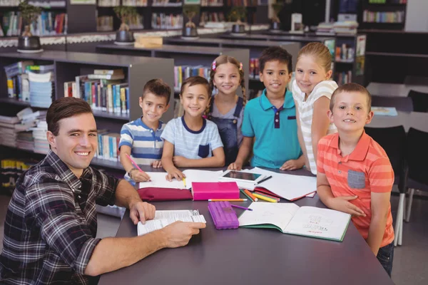 Profesor y escolares que estudian en la biblioteca — Foto de Stock