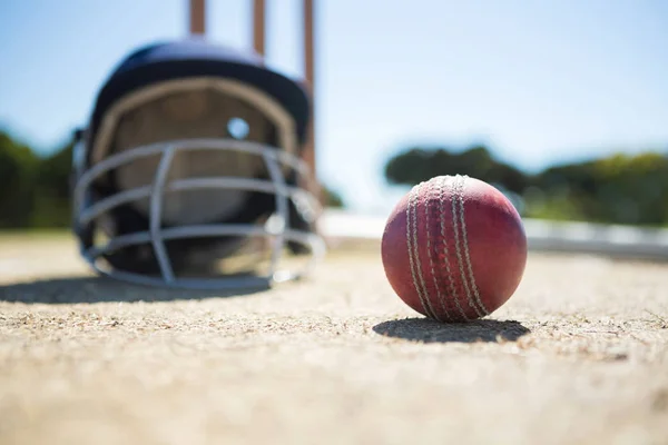Cricketball med hjelm på bek – stockfoto