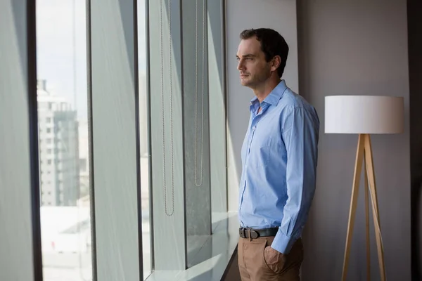 Executivo masculino olhando através da janela — Fotografia de Stock