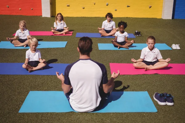 Coach en schoolkinderen beoefenen van yoga — Stockfoto