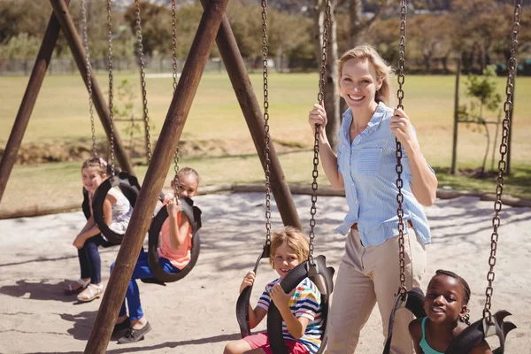 Trainer guiding schoolkids on swing — Stock Photo, Image