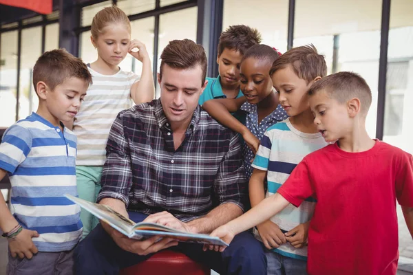 Leraar onderwijs schoolkinderen in bibliotheek — Stockfoto