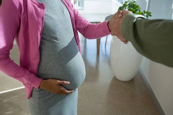 Mulher grávida apertando a mão com colega — Fotografia de Stock